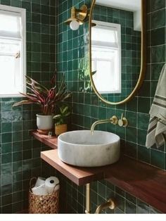 a bathroom with green tiles and a sink in the corner, next to a window