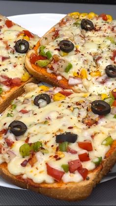 two slices of pizza on a plate with olives, peppers and other toppings