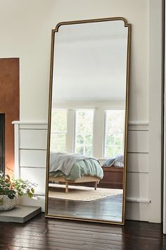 a large mirror sitting on top of a wooden floor next to a fire place in a living room