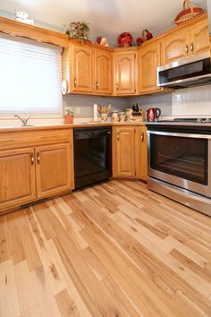 an empty kitchen with wooden floors and stainless steel stove top oven, dishwasher and microwave