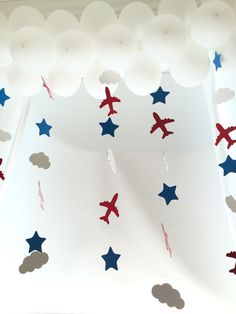 red, white and blue decorations are hanging from the ceiling in an airplane themed room