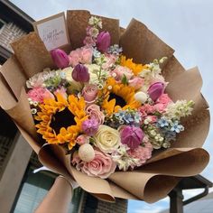 a person holding a bouquet of flowers in front of a house