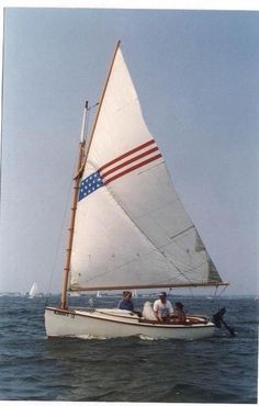 three people in a sailboat with an american flag on it