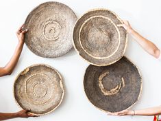 three people are holding baskets with designs on them and one person is reaching for the basket