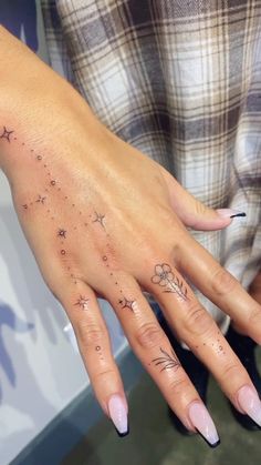 a woman's hand with stars and flowers tattooed on the middle of her fingers