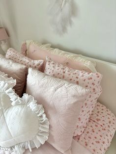 a bed with pink and white pillows on it's headboard next to a clock