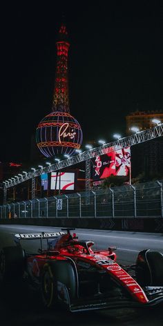 a red race car is parked in front of the eiffel tower at night