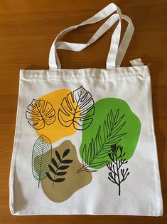 a white bag with leaves on it sitting on a wooden table next to a pair of scissors