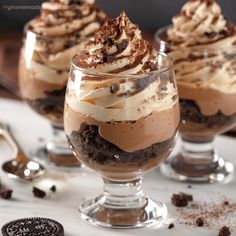 three glasses filled with dessert on top of a table