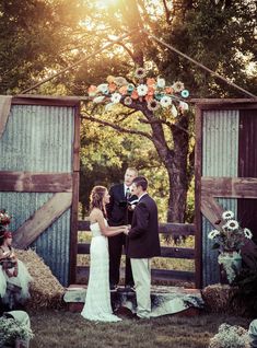 a bride and groom standing in front of an open barn door