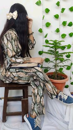 a woman sitting on a stool next to a potted plant