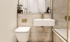 a white toilet sitting next to a sink in a bathroom under a mirror and gold trim