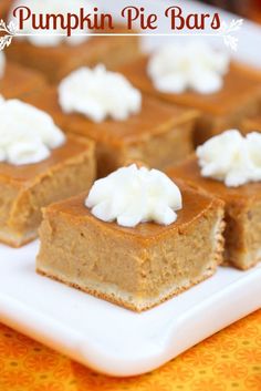 pumpkin pie bars on a white plate with whipped cream in the middle and orange tablecloth