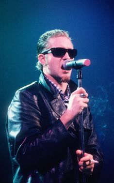 a man with sunglasses on singing into a microphone