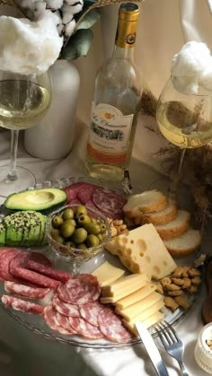 an assortment of cheeses, meats and bread on a platter with wine