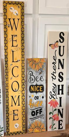 three wooden signs with words painted on them, one saying welcome and the other saying be nice