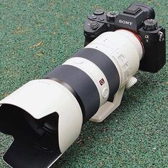 a camera with a lens attached to it sitting on top of a green carpeted floor