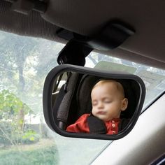 a baby is sleeping in the back seat of a car while looking at its reflection