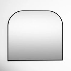 an oval mirror hanging on the wall with a black frame and white walls behind it