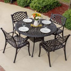 an outdoor dining table with six chairs and plates on it next to a swimming pool