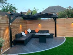 an outdoor living area with couches, tables and lights on the side of it