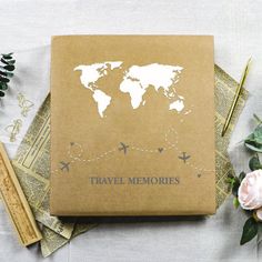 the travel memories book is next to some flowers and other items on top of a table