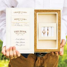 a man holding an open ring box with two wedding rings in it's middle