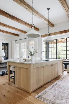 a large kitchen with an island in the middle and wooden beams on the ceiling above it