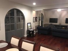 a living room and dining area with wood floors, blue couches and white chairs