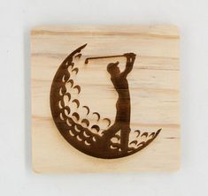 a wooden plaque with a silhouette of a man swinging a golf club on the moon