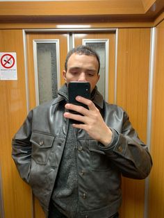 a man taking a selfie in front of a mirror with his cell phone up to his ear