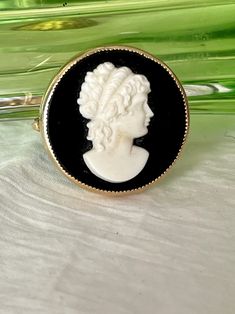 This lovely vintage cameo has a traditional raised design in white with black background. Circle shape gives it a bit of modern twist. The cameo is made of glass, not lucite.  1 1/8" diameter This is in wonderful vintage condition! Questions invited. Add this to your own jewelry collection or gift sustainable to the vintage lover in your life. Follow me on Instagram @gababoutvintage  Is there something in my shop that you've fallen in love with but it's a little out of your price range? Just message me and make an offer. I'm usually willing to negotiate on prices. I'm in business to sell vintage items, not store them...LOL! Also, be sure to ask about wholesale discount prices for orders of 4 or more items. The more you buy, the more you save! DM for details Luxury Cameo Brooch, Background Circle, Black And White Vintage, Fallen In Love, Vintage Cameo, Cameo Brooch, Price Range, Vintage Lover, Circle Shape