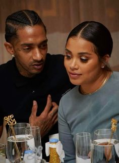 a man and woman sitting next to each other at a table with wine glasses on it