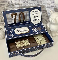 an open box with some chocolates in it next to a small white cat statue