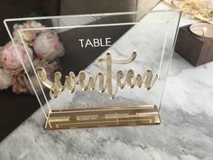 a table that has some flowers on top of it and a sign in the middle