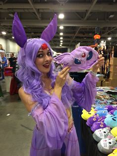 a woman in purple costume holding up a stuffed animal