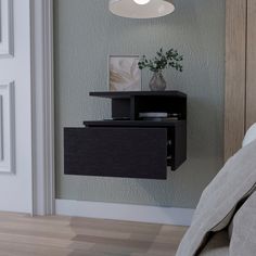 a small black shelf on the side of a wall next to a bed with pillows