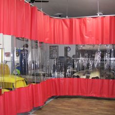 a car showroom with red curtains and yellow chairs