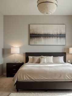 a large bed sitting under a painting on the wall next to two nightstands in a bedroom