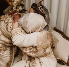 a woman in a wedding dress sitting on a couch with her arms wrapped around her head