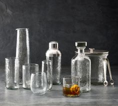 various glassware and bottles are arranged on a counter top, including one with an orange peel in it