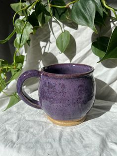 a purple mug sitting on top of a white sheet