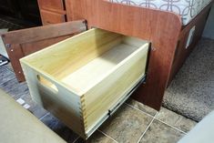 a wooden drawer sitting on the floor next to a bed