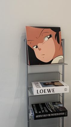 a book shelf with books on it next to a wall mounted anime character poster in the corner