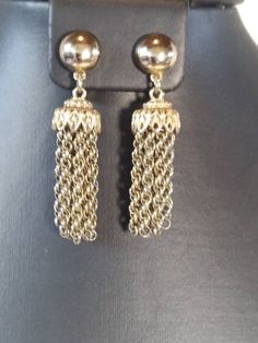 The Beautiful MONET Tassel Earrings are a great example of what made Monet pieces special. The quality, design and craftsmanship really shows. These earrings can be worn casually or easily dressed up for the office, even an evening out! The earrings are gold toned, with a round button at the top and a beautiful tassel hanging from it. The tassels have an intricate filigree design at the top with 10 Prince of Wales chains forming the tassel. I dated these around the late 1940s to early 50s as the Elegant Latkans Earrings For Formal Occasions, Elegant Metal Tassel Earrings, Formal Dangle Tassel Earrings, Elegant Formal Chandelier Earrings With Latkans, Formal Dangle Tassel Earrings With Latkans, Elegant Yellow Gold Earrings With Tassels, Yellow Gold Tassel Dangle Earrings, Gold Tassel Dangle Earrings For Formal Occasions, Formal Metal Tassel Drop Earrings