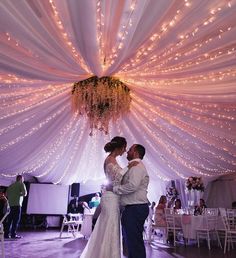 a bride and groom share their first dance under the draping at their wedding reception