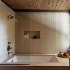 a bath tub sitting under a window next to a sink and counter top with soap dispensers on it