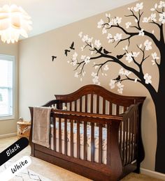 a baby's room with a crib and tree decal on the wall