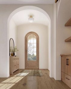 an empty hallway with wooden floors and arched doorway leading to another room in the house