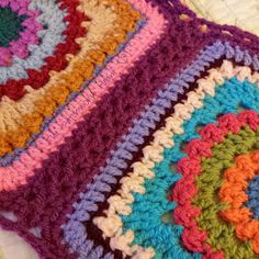 a crocheted granny blanket with multicolored squares